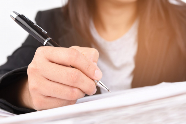 person in a suit writing on a document