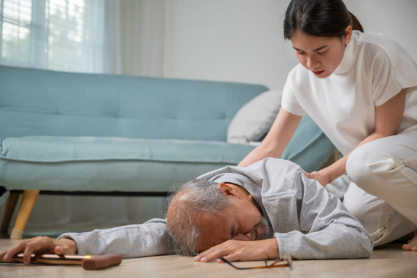 older person fallen on the ground with a younger person helping them up