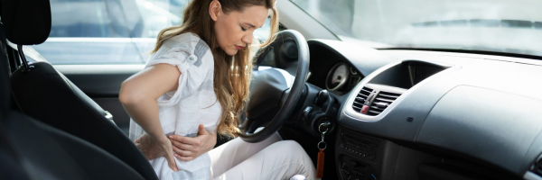 Person sitting in car, twisting to hold back in pain